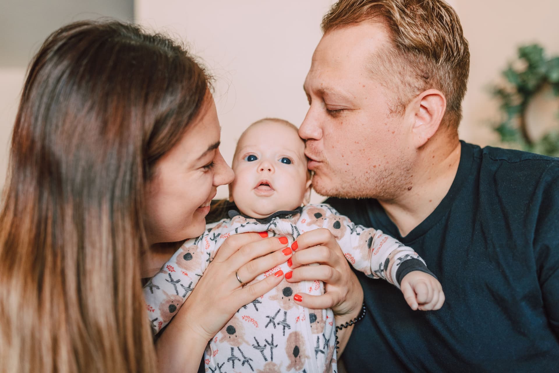 A mother and father holding and kissing their newborn baby