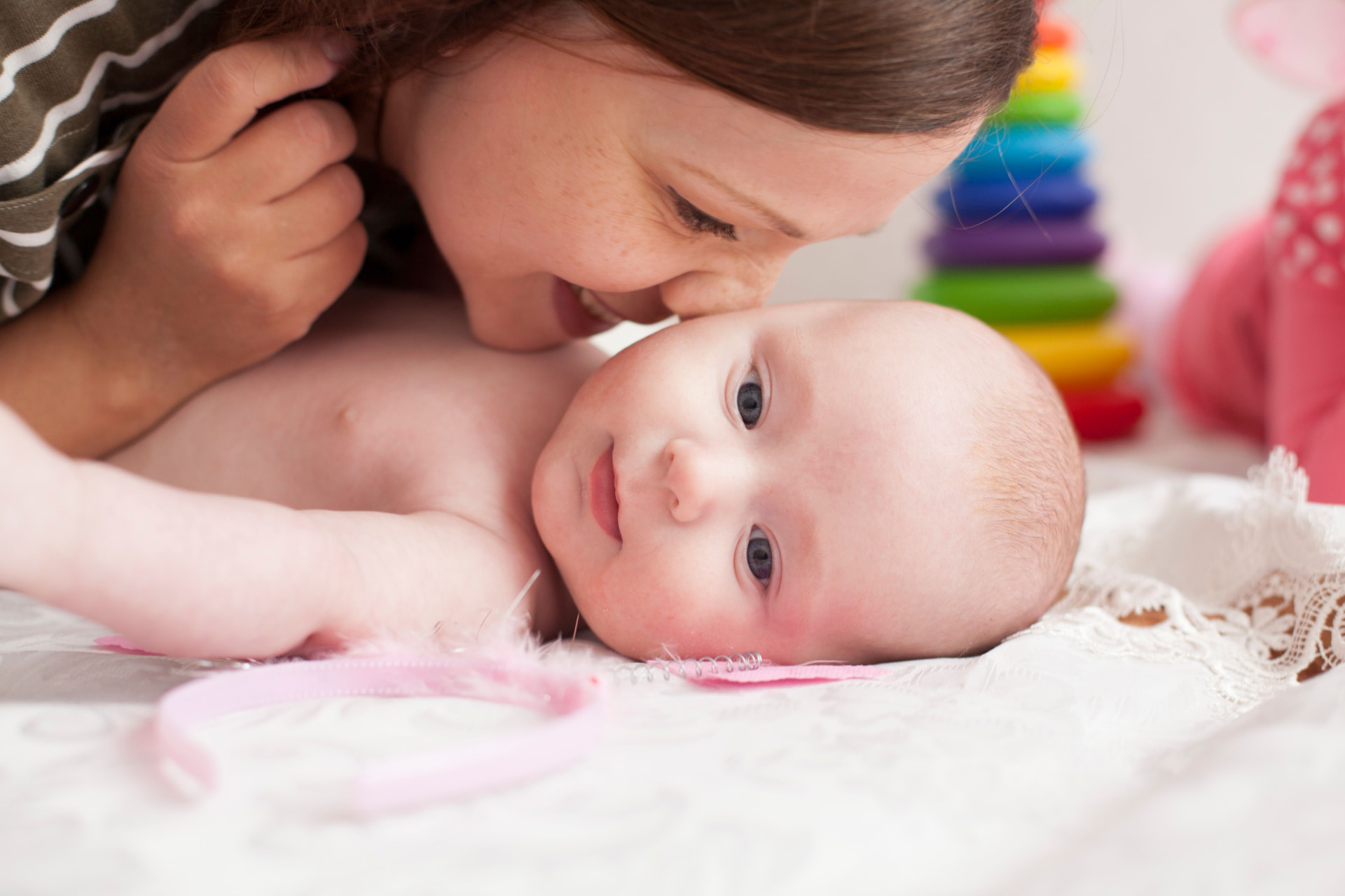 A mother kissing her baby's forehead at home